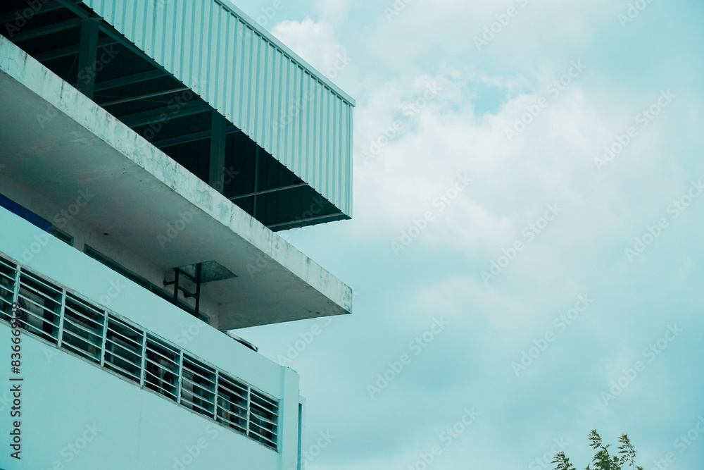 Obraz premium A tall building with a balcony and a cloudy sky in the background