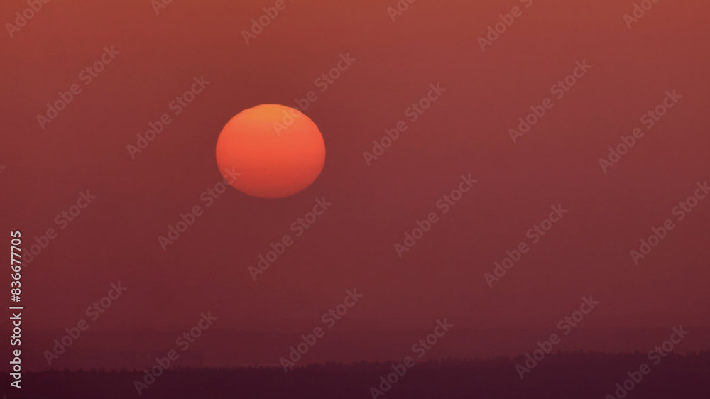 Fototapeta premium The sun sets in the mysterious haze of the evening red sky