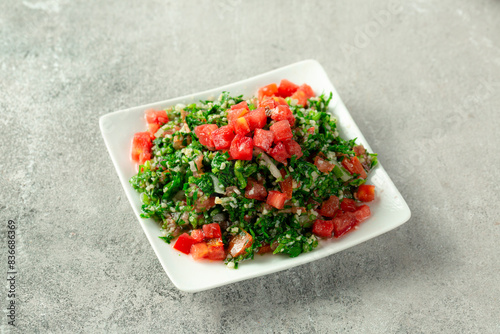 Tabbouleh salad, Eastern Arab appetizers, Maftoul with vegetables, on gray background  photo