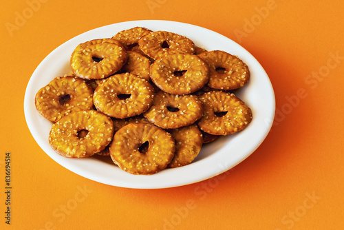 Round crackers with a hole and salt on an orange background