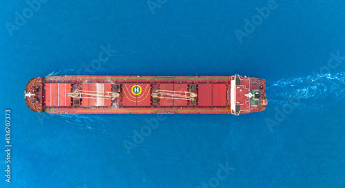 A bulk carrier freight ship at traveling on full motion over blue sea . Aerial view drone photo