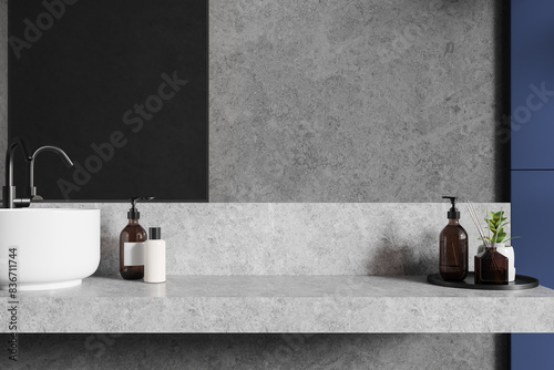 Grey modern hotel bathroom interior with sink and accessories on counter closeup