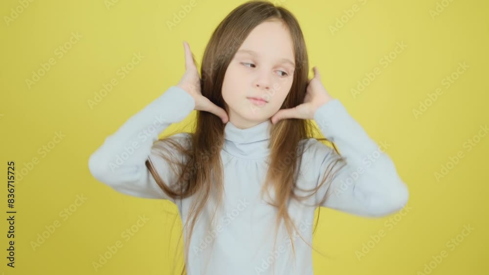 Cute 8-9 year old girl straightens her long hair, preens at the camera on a yellow background. Cute 8-9 year old girl straightens her long hair, preens at the camera on a yellow background.