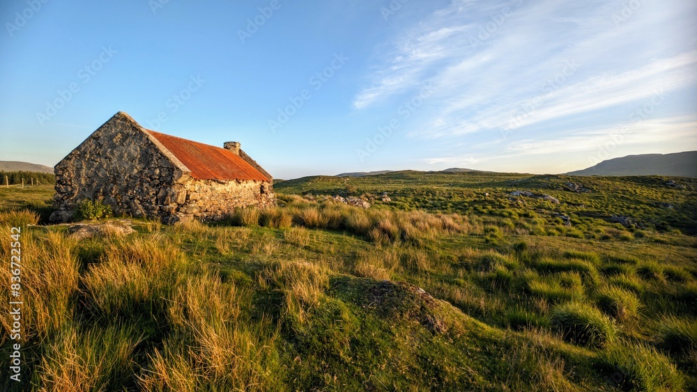 Beautiful landscape scenery with old rusty tin roof cottage on green hill at Connemara National park in County Galway, Ireland