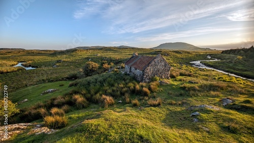 Obraz na płótnie Beautiful landscape scenery with old rusty tin roof cottage on green hill at Connemara National park in County Galway, Ireland w salonie