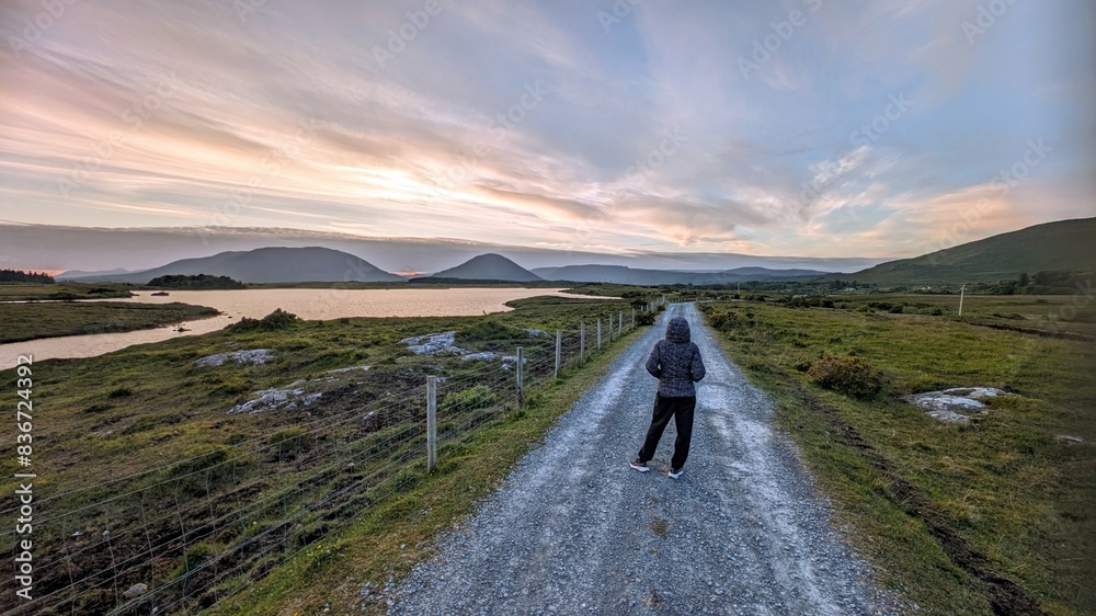 Girl hiker on Empty rural road by lake and mountains at Connemara national park, Galway, Ireland