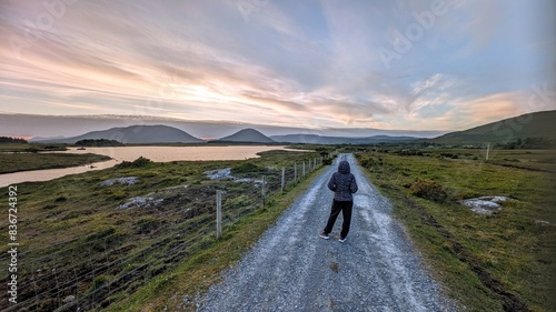Obraz na płótnie Girl hiker on Empty rural road by lake and mountains at Connemara national park, Galway, Ireland w salonie