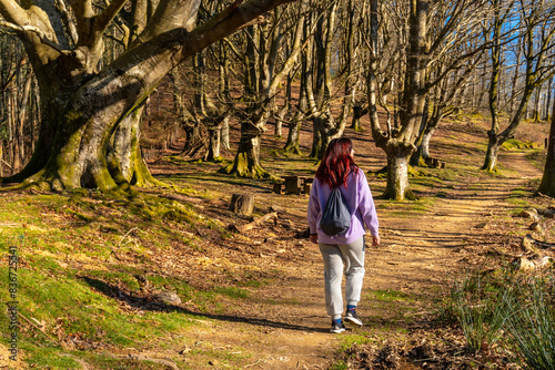 A woman walks through a forest with a backpack on her back © unai