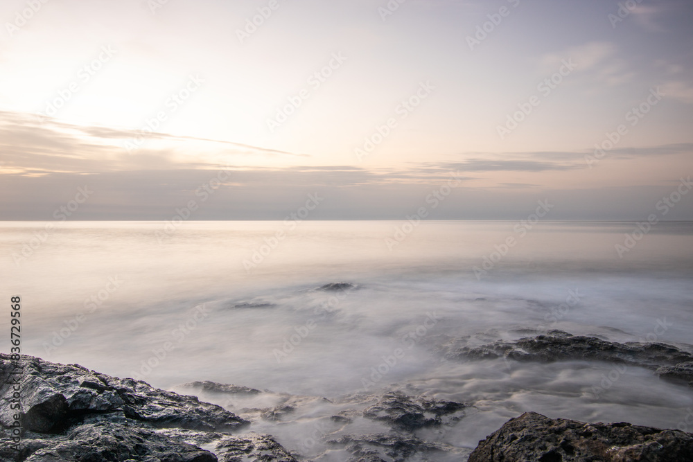 Sunrise with a sea view on a rocky coast in warm colors. Landscape with a lava stone beach at Tarajalejo on Fuerteventura, Canary Islands, Spain. Sunrise with a sea view on a rocky coast in warm colors. Landscape with a lava stone beach at Tarajalejo on Fuerteventura, Canary Islands, Spain.