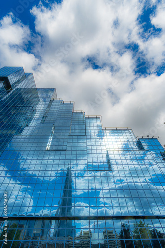 Northern Shell's avant-modern blue-glazed office building on London's River Thames promenade with the reflection of clouds, the sky and the Shard skyscraper on its facade.