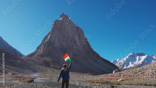 Rear View shot of an Indian flag waving the flag of India in front of Gonbo Rangjon mountain at Zanskar in Ladakh, India. Man waves Indian flag in the mountains. Patriotic Indian man waving flag. photo