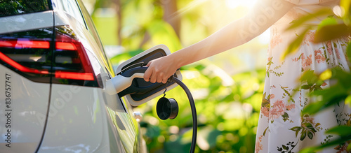 woman is plugging in electric car into a charging station,Charge EV battery at charging point, Sustainable energy. Electric vehicle infrastructure