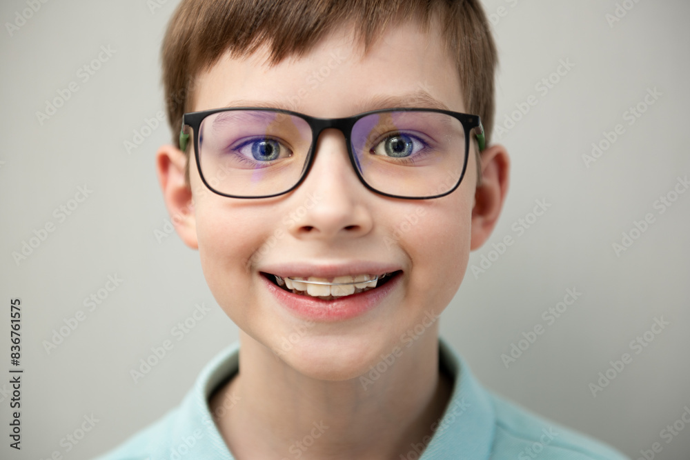 Close-up of a smiling child boy with braces on gray background Close-up of a smiling child boy with braces on gray background