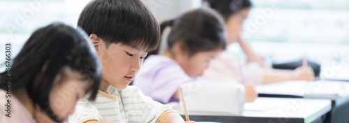 Foto 小学校の教室で勉強する小学生の子供たち　テストや試験を受けるバナー