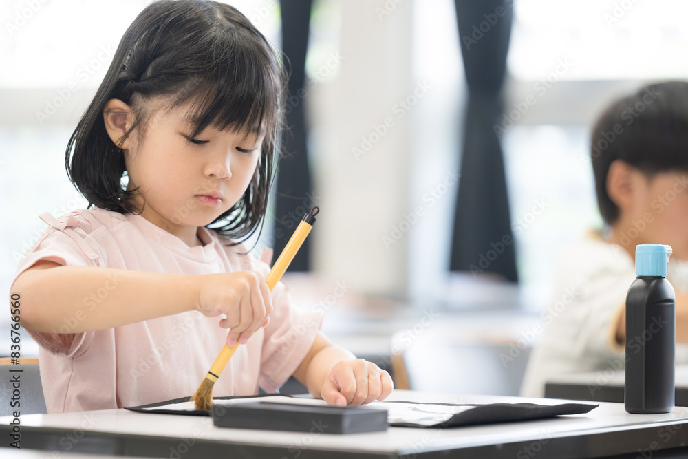 明るい小学校の教室で習字を教わる小学生の女の子 クローズアップ 明るい小学校の教室で習字を教わる小学生の女の子 クローズアップ