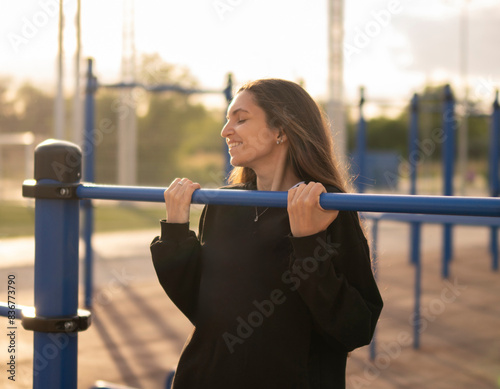 Woman Doing Pull-Ups On Outdoor Exercise Bar Equipment, low angle
