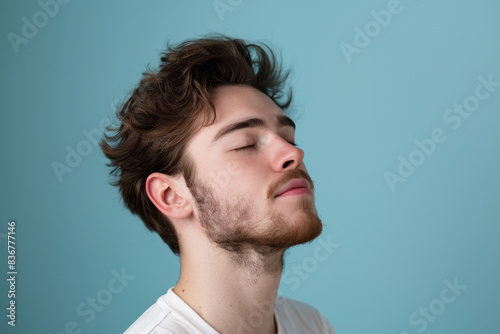 A close up of a man with beard and closed eyes looking to a side