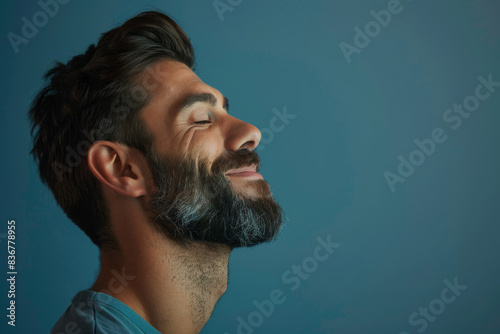 A close up of a man with beard and closed eyes looking to a side