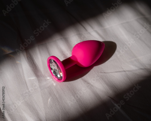 Pink silicone anal plug on a white sheet. 