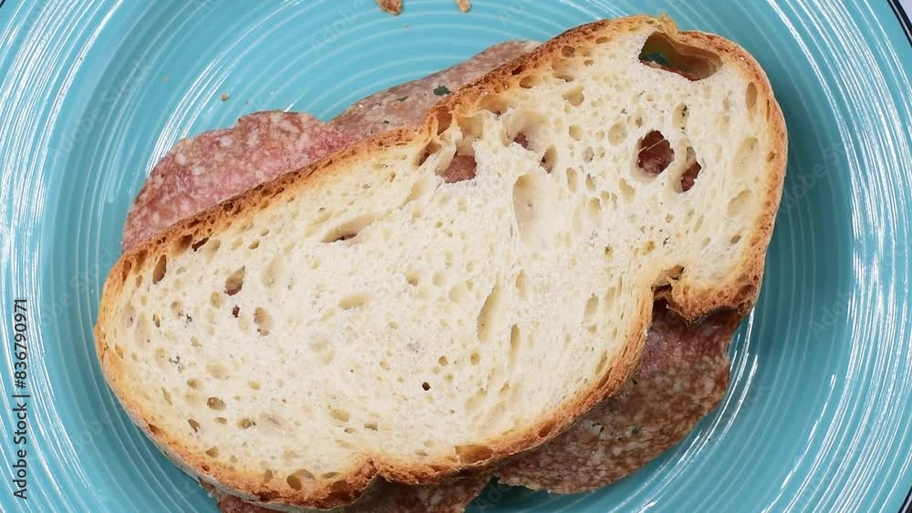soft wheat bread with slices of Hungarian salami,rustic sandwich with cold cuts.Pane di grano tenero con fette di salame Ungherese,panino rustico con affettati,close-up,rotating video