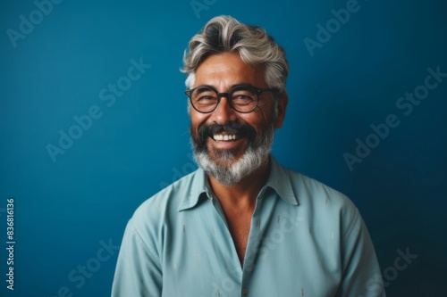 Portrait of a Smiling Senior Man Wearing Glasses Posing by the Blue Wall © alisaaa