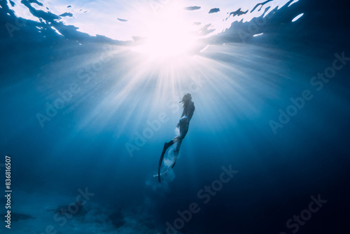 Freediver girli with diving fins and amazing sun rays.