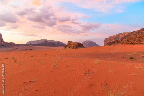 Breathtaking sunset paints the sky with pastels over Jabal Al Qattar cliff  alongside the iconic the Seven Pillars of Wisdom rock formation in the majestic Wadi Rum desert of Jordan