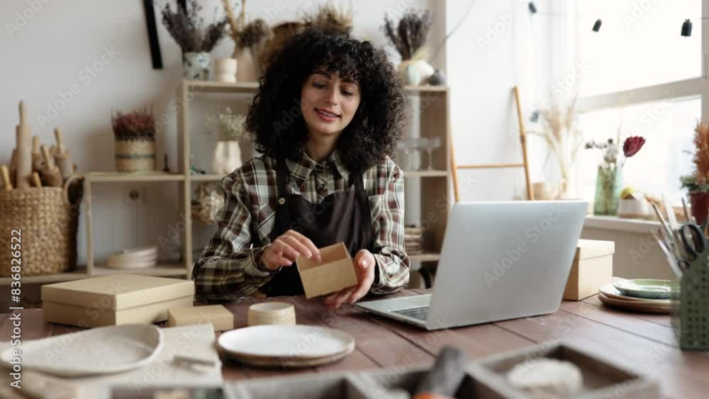Small business selling goods on the Internet. Entrepreneur sells dishes, plates and cups made of clay, ceramics online and packs them in boxes for sending to the delivery service.