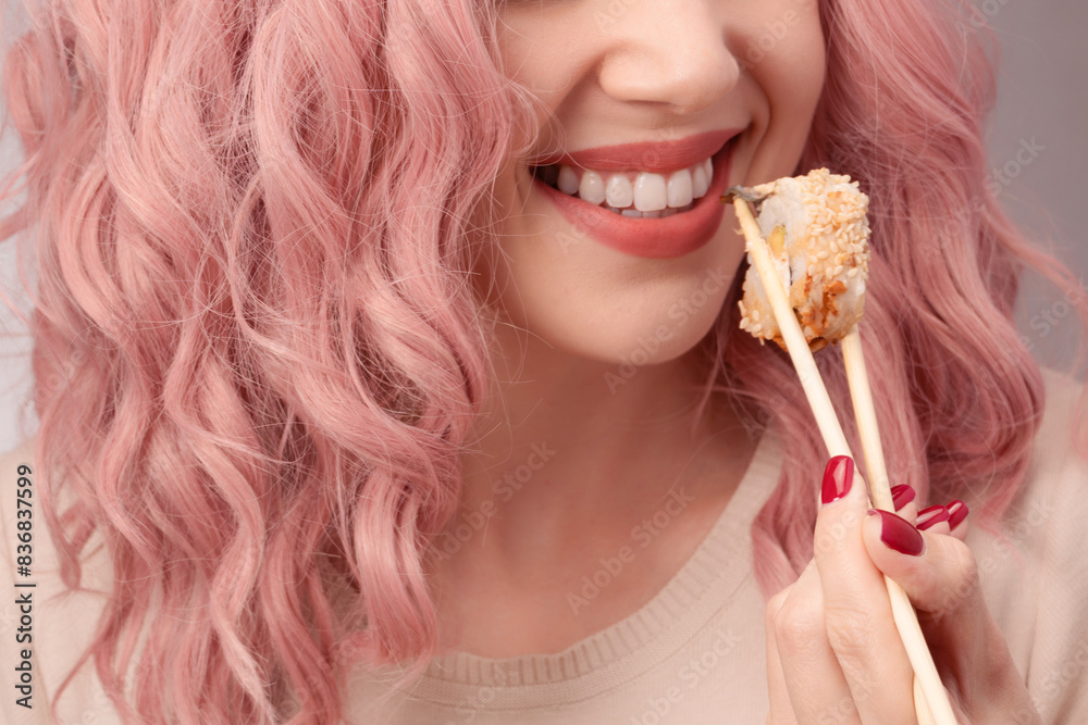 Young woman with red nails and pink hair is eating sushi. Young woman with red nails and pink hair is eating sushi.