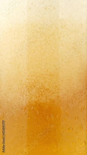 Cold beer with foam pouring in glass, macro