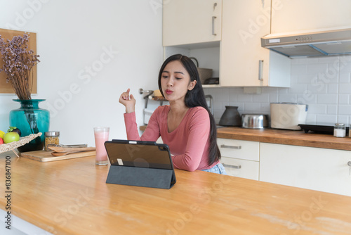 Asian woman working and eating in home kitchen counter busy work from home