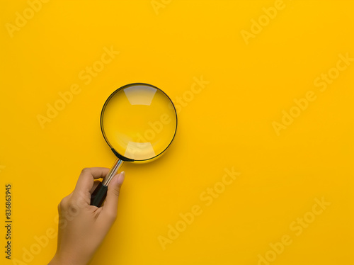 Hand Holding Magnifying Glass on Yellow Background with Copy Space (generative AI) photo