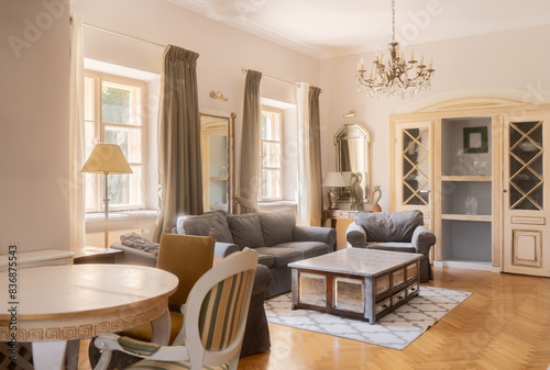 Fotografie A spacious living room featuring elegant vintage decor, a chandelier, and large windows letting in natural light