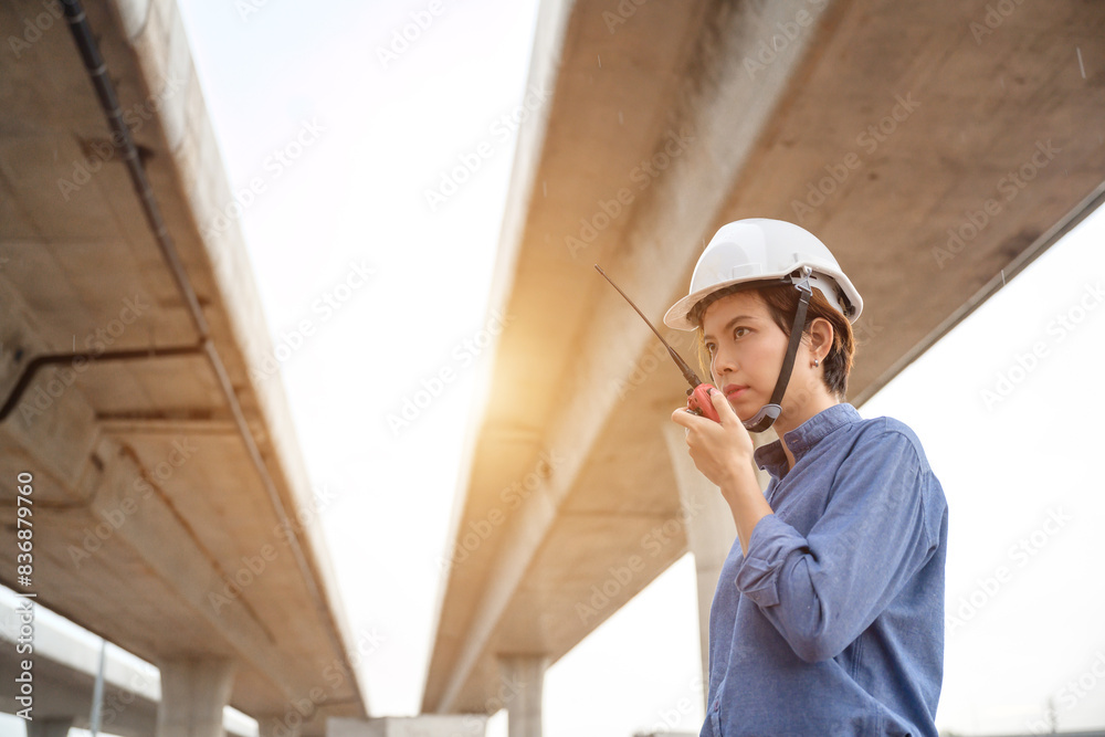 Asian female architect talking with radio at construction site in expressway road construction Female engineers inspect road construction work and supervise new roads as civil engineers. Asian female architect talking with radio at construction site in expressway road construction Female engineers inspect road construction work and supervise new roads as civil engineers.
