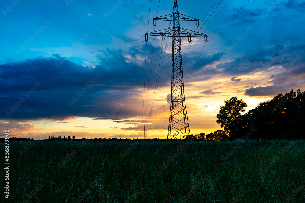 Abend am Stadtrand. Die Sonne leuchtet durch die dunklen Wolken im Vordergrund befindet sich ein Strommast. Abend am Stadtrand. Die Sonne leuchtet durch die dunklen Wolken im Vordergrund befindet sich ein Strommast.