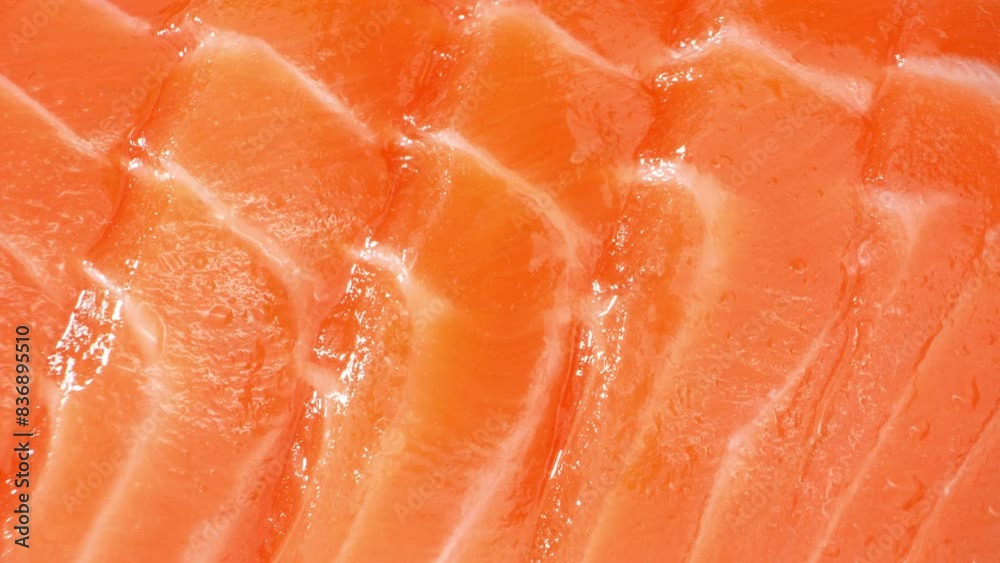 Thinly sliced salmon, with its rich orange pigment, showcases exquisite marbling. Each delicate layer glistens under light, underscoring its premium quality and impeccable freshness.
