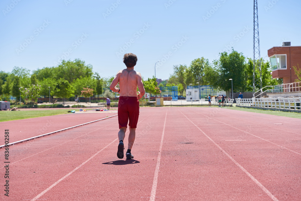 Fototapeta premium man training on a running track. general view of a shirtless man running.