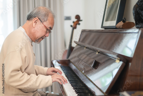 Happy relaxation Asian senior retirement man with eyeglasses learn to play piano at home, elderly old man playing music on piano in living room, lifestyle life after retirement, Close up hands