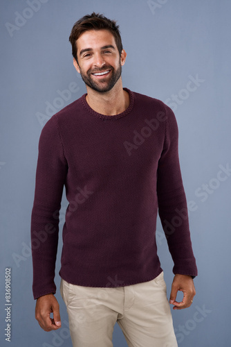 Studio, jersey and portrait of man, confidence and sweater for fashion, pride and cardigan in winter. Blue background, cheerful and person in Miami, smile and comfortable in clothes, happy and joy