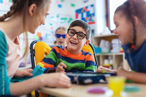 A teacher assists a student with a learning disability using an adaptive communication device in an inclusive classroom. Students of different abilities work together in a supportive and collaborative