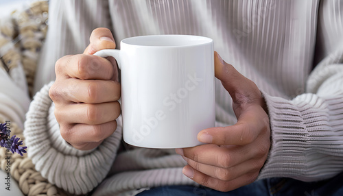 Man holding white mug indoors, closeup. Mockup for design