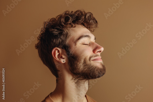 A close up of a man with beard and closed eyes looking to a side