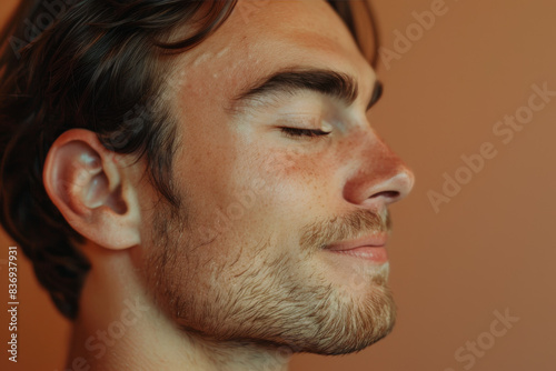 A close up of a man with beard and closed eyes looking to a side