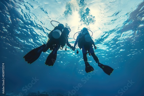 Two divers in scuba gear swimming underwater, exploring marine life