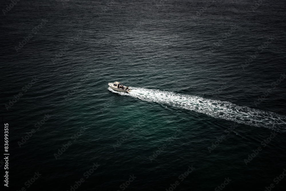 Naklejka premium Boat sailing on Atlantic ocean and leaving white trail. Selective focus. Travel concept