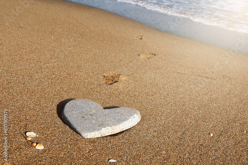 Stone in the shape of heart on sandy beach during summer trip. Heart-shaped stone on the sandy shore, symbolizing love and affection by the ocean