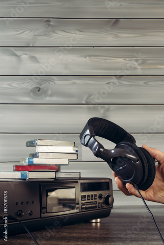 Man using headphones to listen music on old cassette tape recorder. Retro media: Wooden cassette player and tapes, great for vintage audio equipment designs