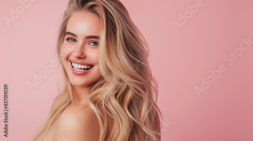young smiling woman with blonde long hair isolated on pastel pink background