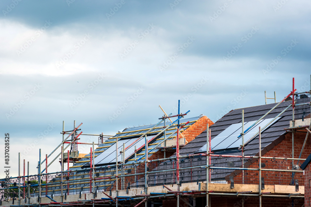 Fototapeta premium Photovoltaic solar panels on the roof of new built house in england uk. The concept of a sustainable environment, construction
