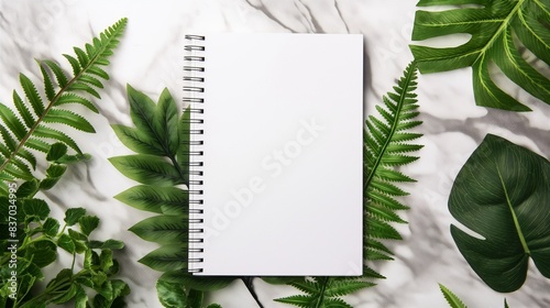 A blank white spiral notebook with leaves and plants on the sides